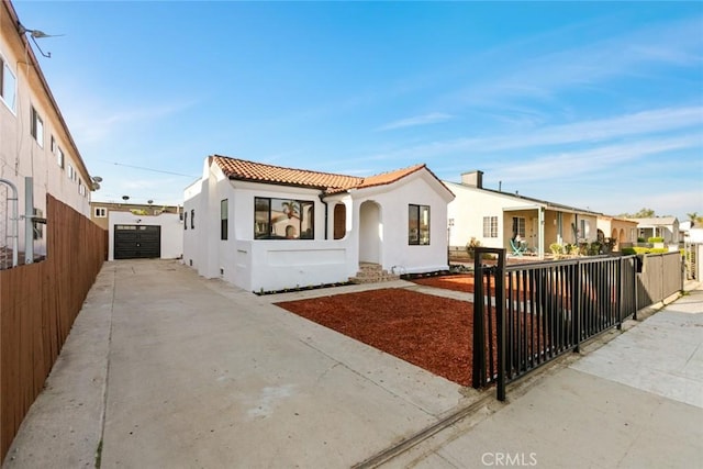 mediterranean / spanish home with stucco siding, concrete driveway, a tile roof, and fence