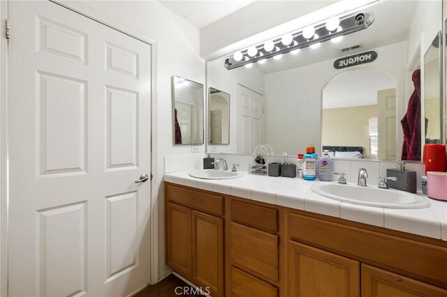 bathroom with visible vents, a sink, and double vanity
