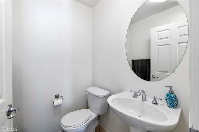 bathroom featuring toilet, a sink, and baseboards