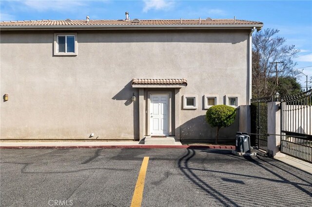 rear view of property with uncovered parking, stucco siding, and fence