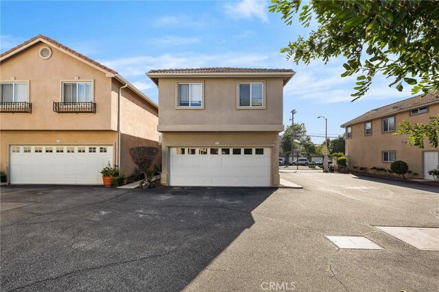 view of front of house featuring stucco siding, an attached garage, and aphalt driveway