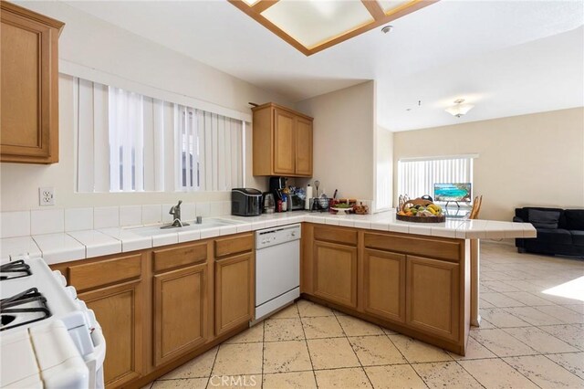 kitchen featuring a sink, brown cabinetry, open floor plan, white appliances, and a peninsula