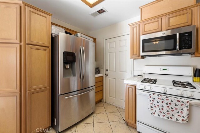kitchen featuring tile countertops, appliances with stainless steel finishes, visible vents, and light tile patterned floors