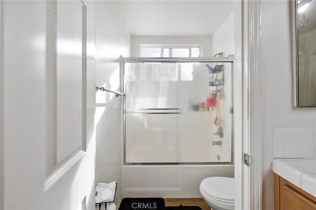bathroom with vanity, enclosed tub / shower combo, and toilet