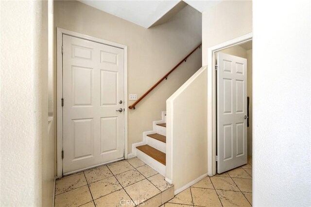 entryway with baseboards, light tile patterned flooring, and stairs