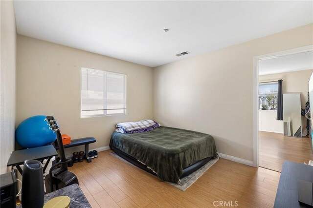 bedroom with wood finished floors, visible vents, and baseboards
