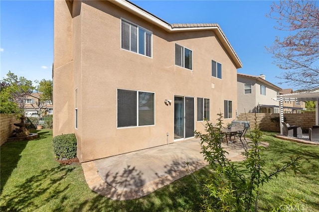back of property with a patio area, stucco siding, and fence