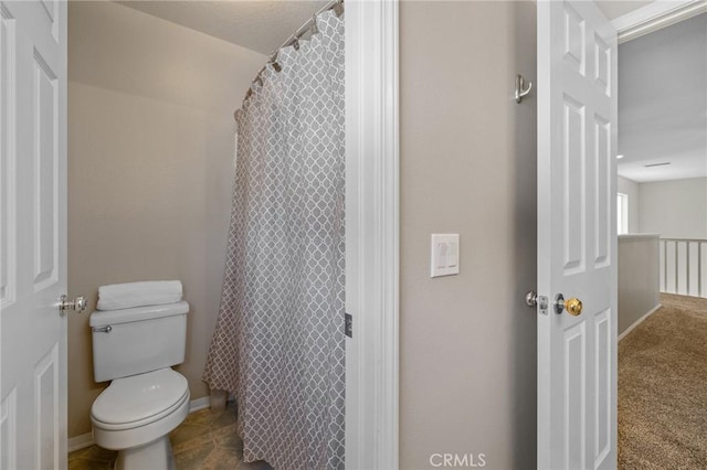 bathroom featuring toilet, curtained shower, and baseboards