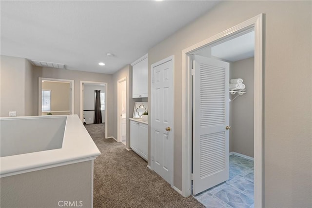 corridor featuring baseboards, recessed lighting, carpet flooring, visible vents, and a sink