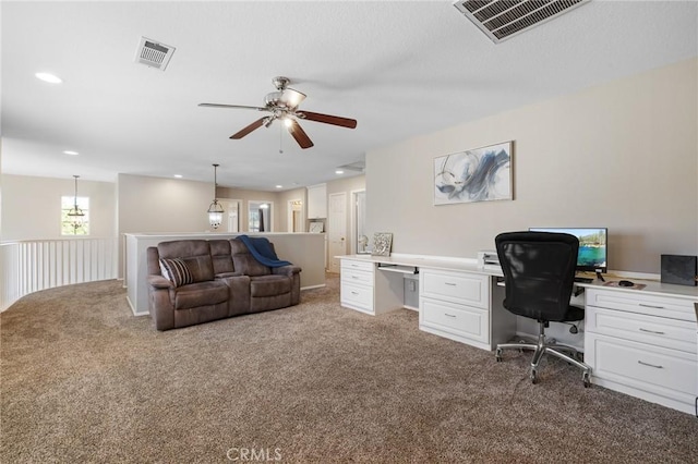 carpeted office featuring built in desk, visible vents, and a ceiling fan