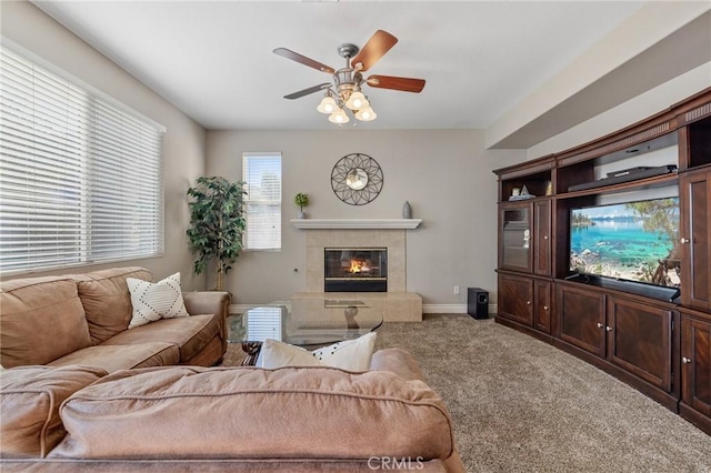 living room featuring carpet flooring, a tile fireplace, baseboards, and a ceiling fan