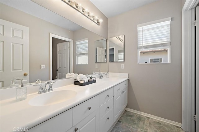 full bath featuring double vanity, a sink, and baseboards