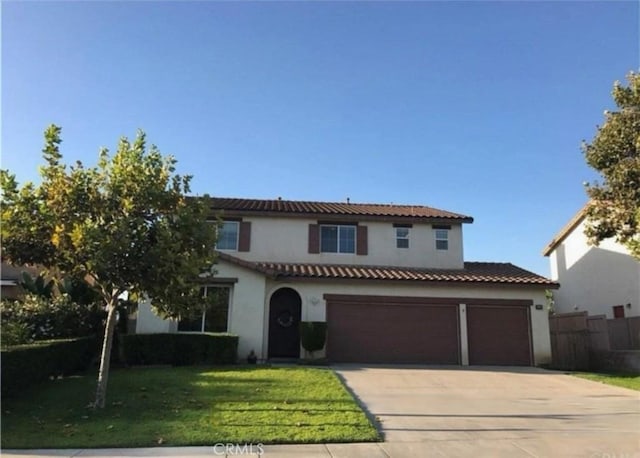 mediterranean / spanish home with driveway, an attached garage, a front yard, a tile roof, and stucco siding