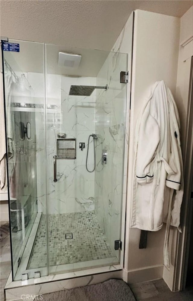 full bath with a marble finish shower, baseboards, a textured ceiling, and wood finished floors