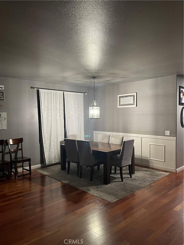 dining room featuring a textured ceiling and dark wood finished floors