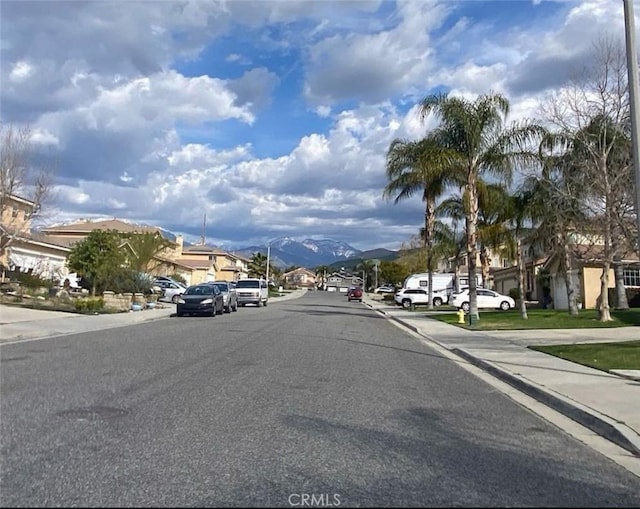 view of road featuring curbs, a mountain view, street lighting, and sidewalks