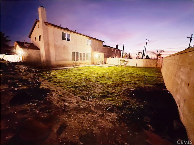 yard at dusk featuring a fenced backyard