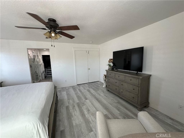 bedroom with baseboards, a textured ceiling, light wood-style floors, and ceiling fan