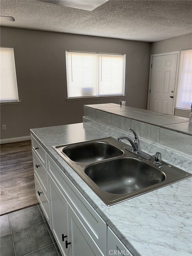 3408 20th St, Highland, CA 92346 - kitchen featuring a sink, a textured ceiling, white cabinets, healthy amount of natural light, and dark tile patterned floors