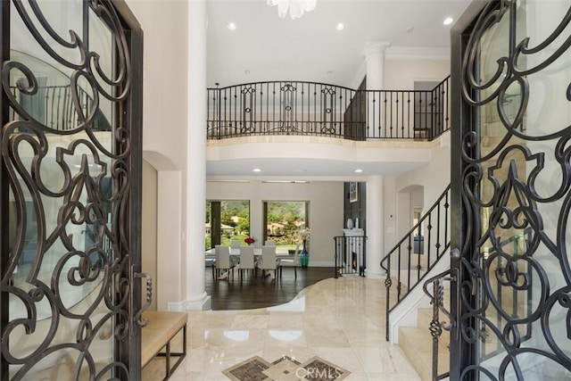 foyer with ornate columns, arched walkways, ornamental molding, recessed lighting, and stairway
