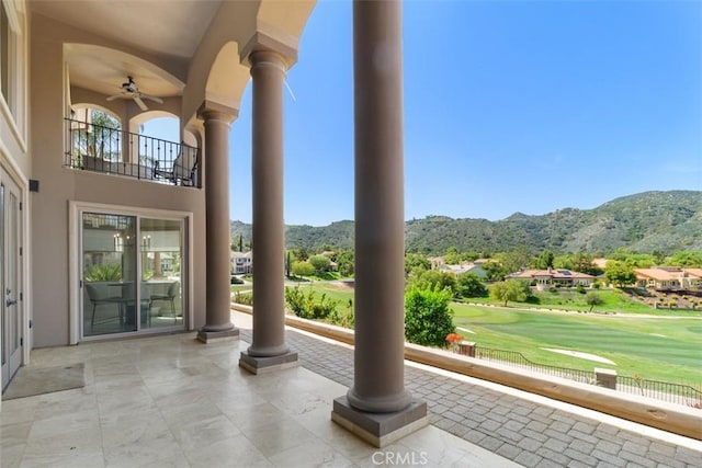 view of patio featuring a mountain view, view of golf course, and a balcony