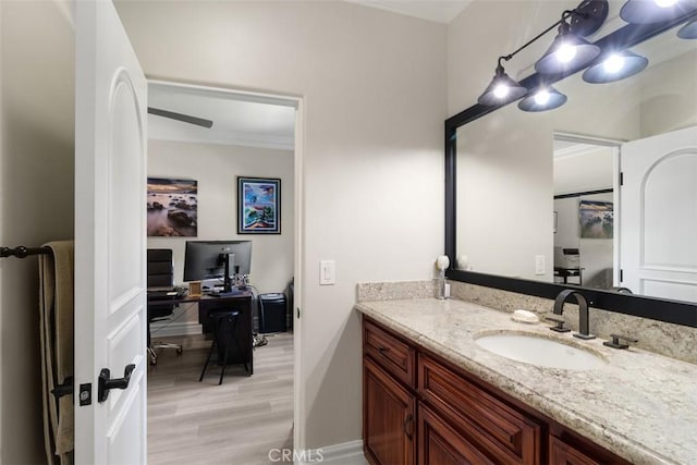 bathroom featuring wood finished floors, vanity, baseboards, and ornamental molding