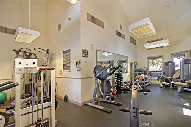 gym with a high ceiling, baseboards, and visible vents