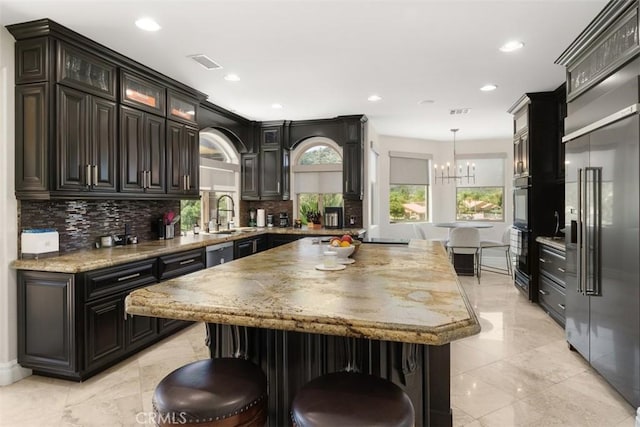 kitchen with visible vents, a notable chandelier, stainless steel appliances, decorative backsplash, and a breakfast bar area