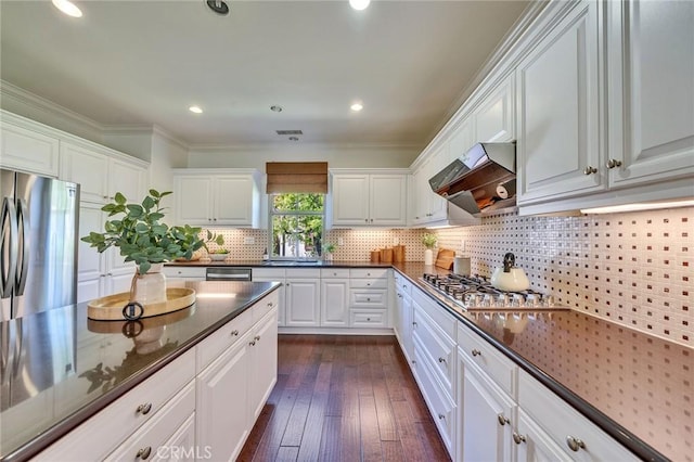 37 Fanpalm, Irvine, CA 92620 - kitchen with appliances with stainless steel finishes, custom exhaust hood, white cabinetry, dark wood finished floors, and tasteful backsplash