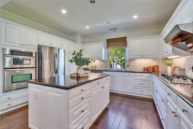 37 Fanpalm, Irvine, CA 92620 - kitchen with appliances with stainless steel finishes, dark countertops, wall chimney range hood, dark wood-style floors, and ornamental molding