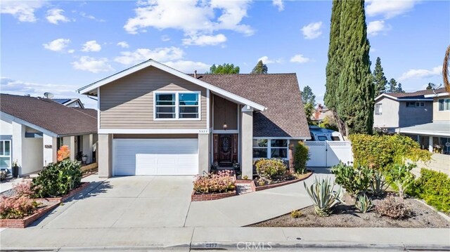 view of front facade featuring a gate, concrete driveway, an attached garage, and fence