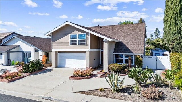 view of front of home featuring fence, roof with shingles, driveway, an attached garage, and a gate