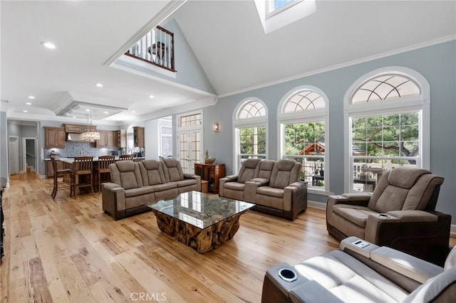 living area with light wood-type flooring, a healthy amount of sunlight, and ornamental molding