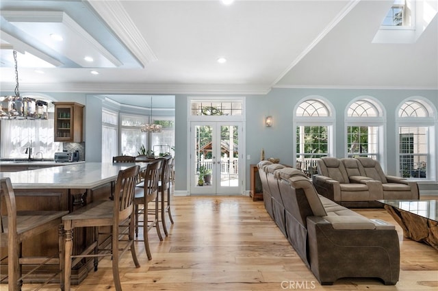 living area with a chandelier, light wood-style floors, a toaster, and french doors