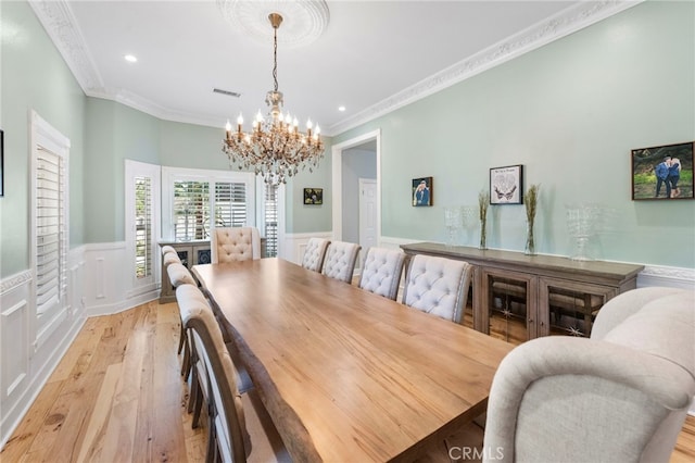 dining room featuring light wood finished floors, a wainscoted wall, visible vents, and a notable chandelier