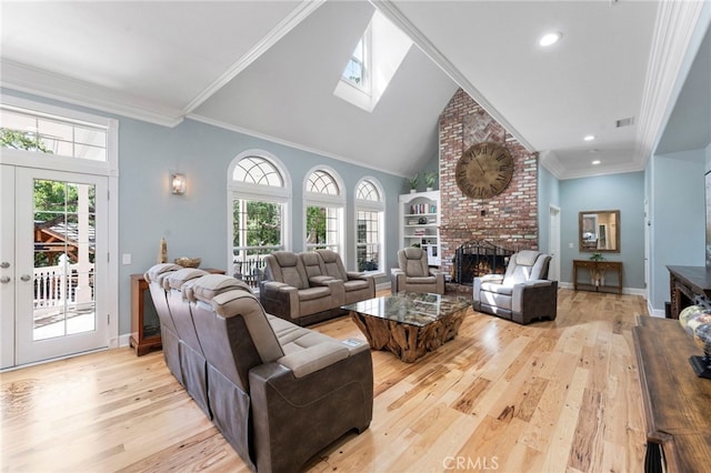 living area with light wood finished floors, a brick fireplace, a wealth of natural light, and visible vents