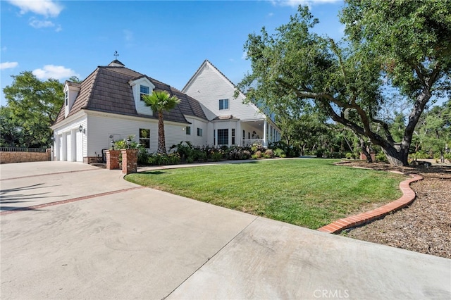 view of front of house featuring concrete driveway, mansard roof, and a front yard