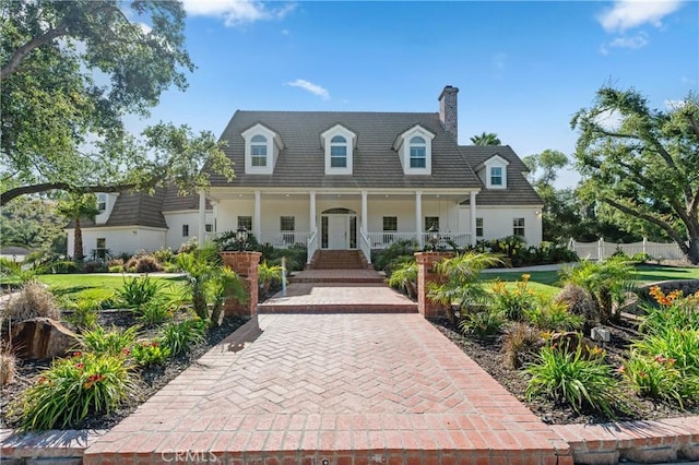 cape cod home featuring fence, a chimney, and covered porch