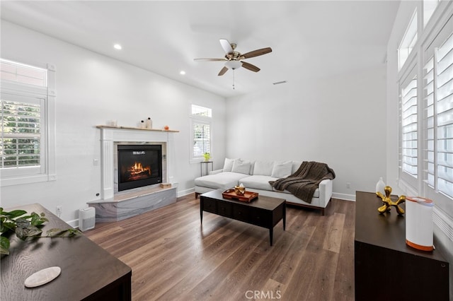 living area featuring a ceiling fan, wood finished floors, a glass covered fireplace, visible vents, and recessed lighting