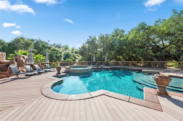 view of swimming pool with fence, a wooden deck, and a pool with connected hot tub