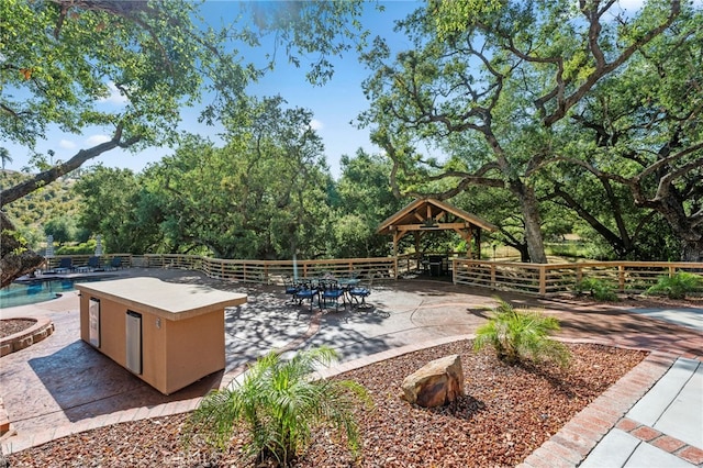 view of patio with fence, an outdoor pool, and a gazebo