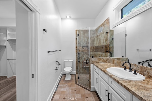 bathroom featuring a shower stall, toilet, vanity, and baseboards