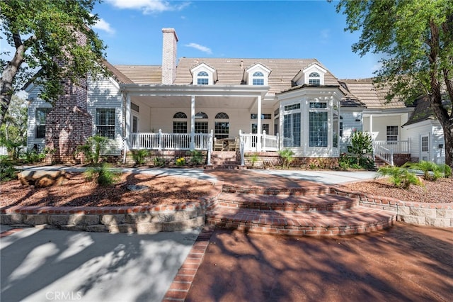 rear view of property featuring a chimney and covered porch