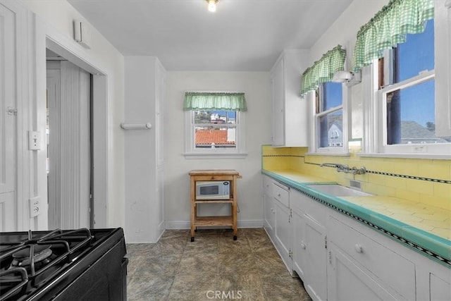 308 Catalina Ave, Avalon, CA 90704 - kitchen with white microwave, a sink, light countertops, white cabinets, and backsplash