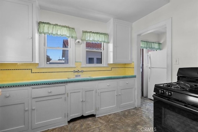 308 Catalina Ave, Avalon, CA 90704 - kitchen with black gas stove, freestanding refrigerator, a sink, decorative backsplash, and white cabinetry