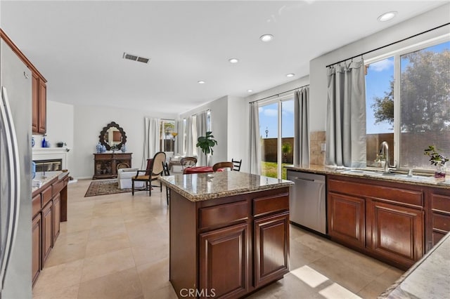 27669 Bluff Vista Way, Menifee, CA 92584 - kitchen with light stone counters, visible vents, a sink, stainless steel appliances, and a center island