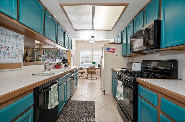 4591 Warner Ave Unit 101, Huntington Beach, CA 92649 - kitchen with black appliances, tile counters, a sink, blue cabinets, and light tile patterned flooring