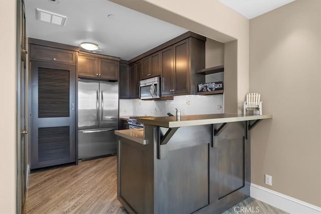 133 Upper Terrace Rd, Avalon, CA 90704 - kitchen featuring tasteful backsplash, dark brown cabinets, appliances with stainless steel finishes, a kitchen breakfast bar, and open shelves