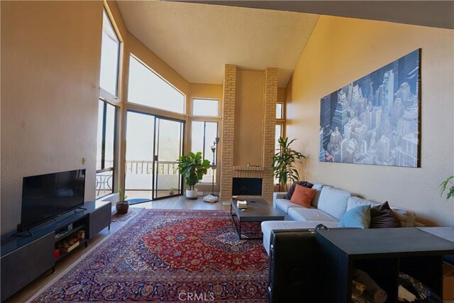 living area with wood finished floors, a high ceiling, a fireplace, and a textured ceiling