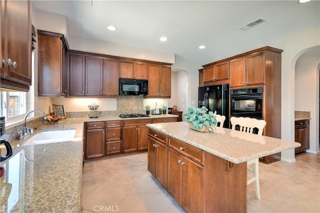 26718 Cactus Creek Way, Menifee, CA 92586 - kitchen with arched walkways, black appliances, a sink, a kitchen breakfast bar, and light stone counters